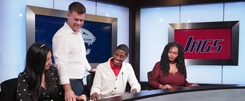 Professor working with students in television studio on campus.