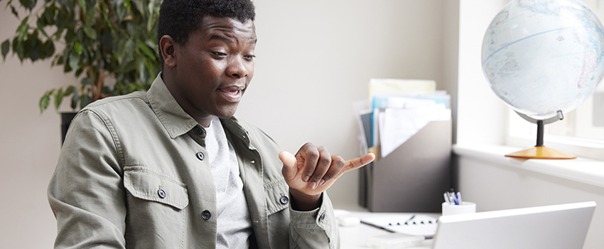 Man doing sign language facing a laptop.