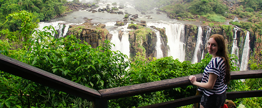 Student smiling in front of waterfall. 