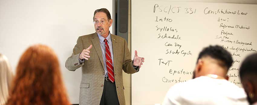 Political Science professor speaking in front of class.