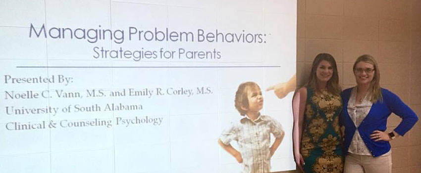 Two females standing in front of a presentation.