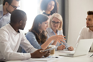 A group of people working at a table on a laptop.