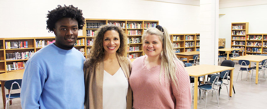 Two students with a school counselor in the library,