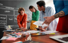 A group of people working on table in front of chalk board.