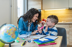 Teacher working at desk with young child smiling.