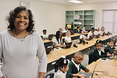 Teacher standing in front of her class while children work at their desks.