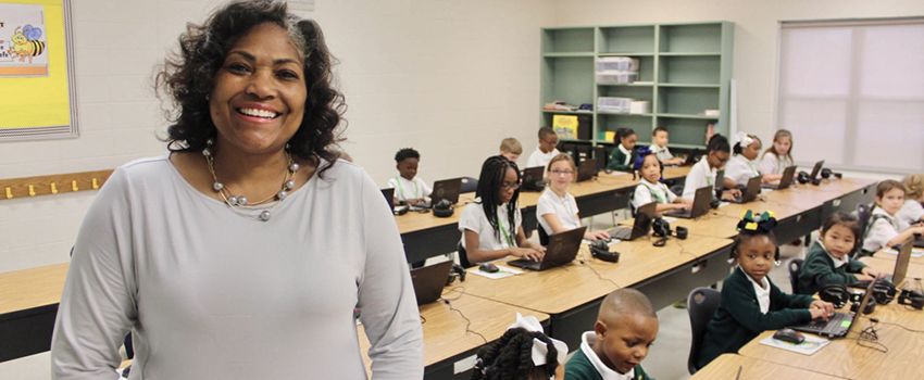 Teacher standing in front of her class of children at desks.