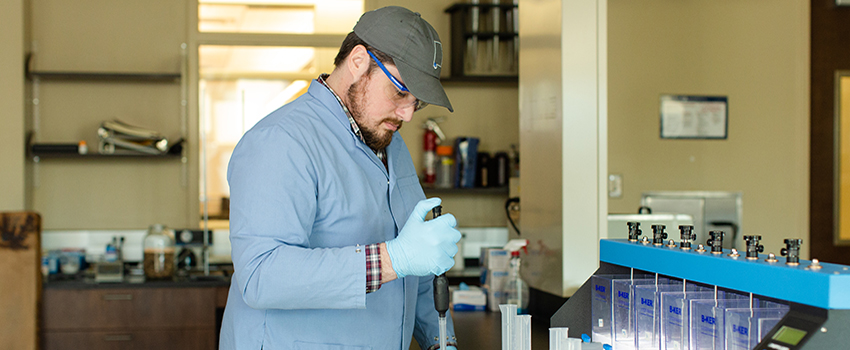 Male student using dropper in lab.