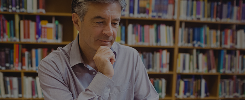 Man with books behind him on bookshelves.