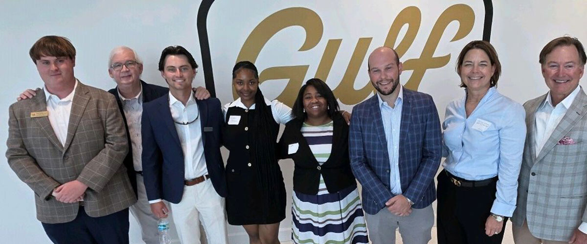 Real Estate students in front of Gulf sign with professionals.