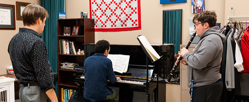 Student playing piano and student playing flute with instructor.