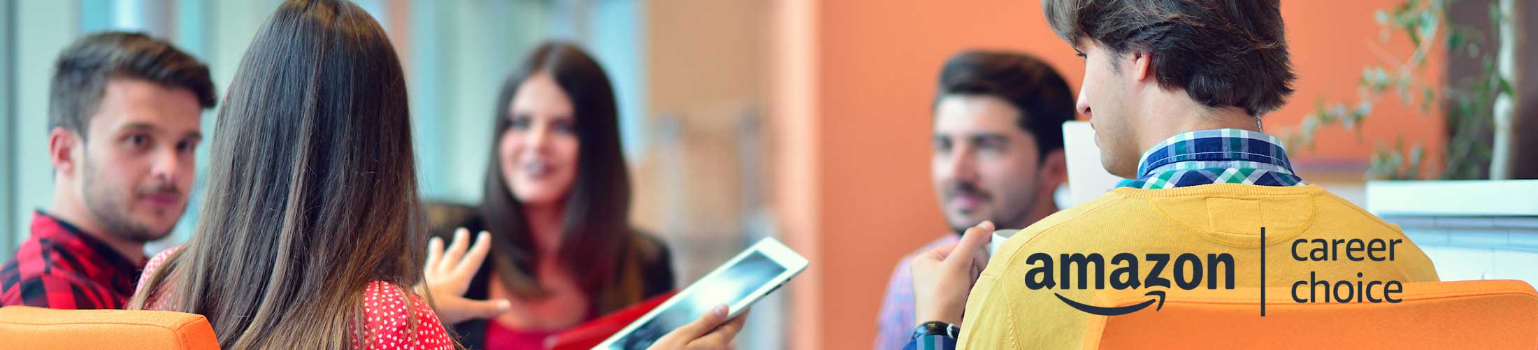 Group of People sitting and talking while one holds a tablet with the Amazon Career Choice logo.