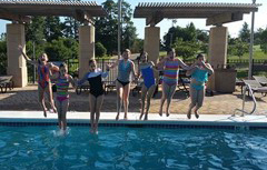 Kids jumping in thye outdoor pool holding hands