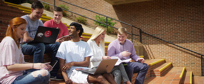 Students sitting outside of the Student Center on the stairs.