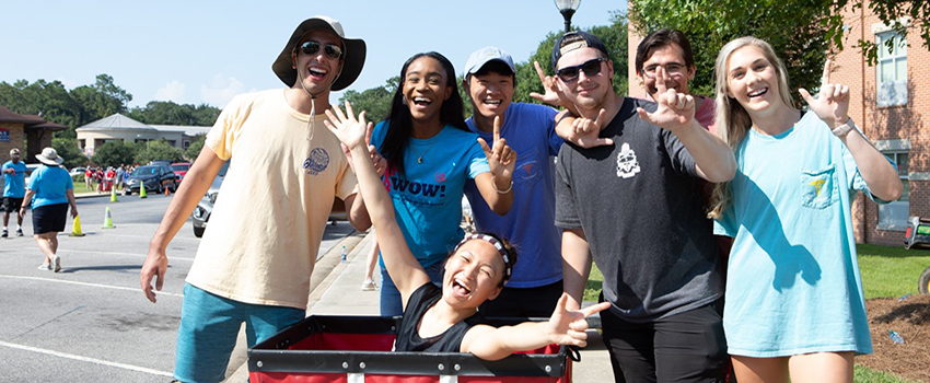 Students at move in day holding up the J sign.