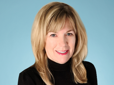 Leigh Delaney-Tucker wearing a black turtleneck in front of a light blue background