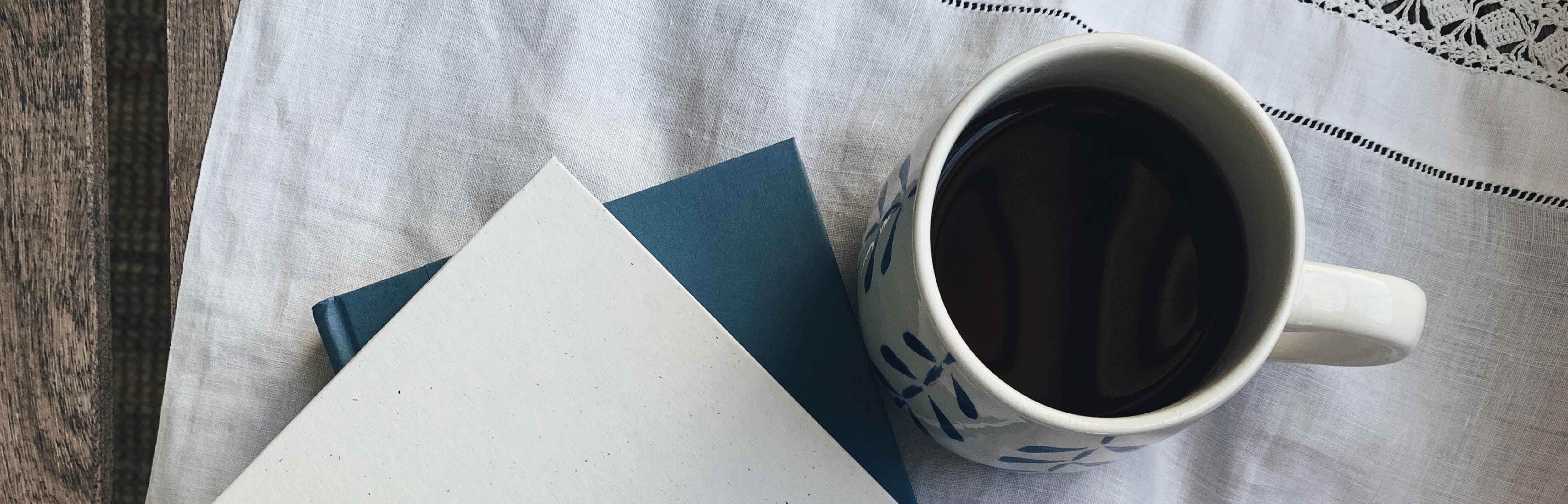 Coffee cup with notebook sitting on table.