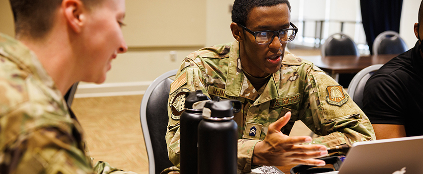 Military students in classroom talking.