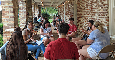 Students sitting outside at tables on campus.