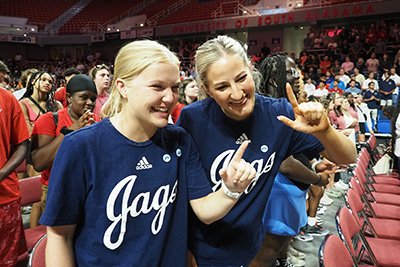 Two students smiling holding up J sign for Jaguars.