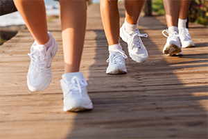 White tennis shoes running on a boardwalk.