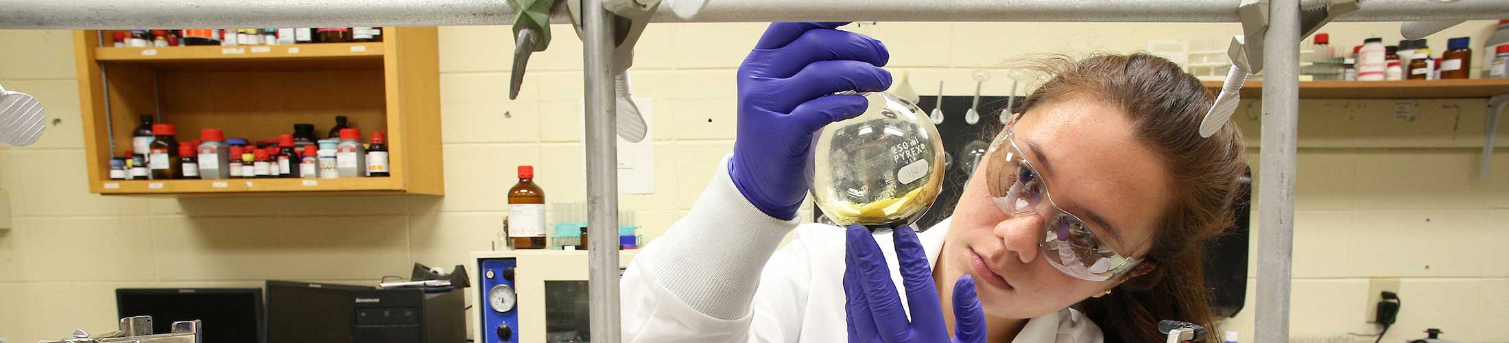 Student working in lab holding a beaker.